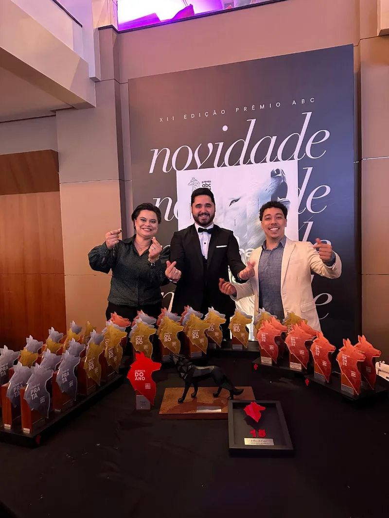 Alex Pinhol com a equipe da Agência WB.P diante da mesa de troféus conquistados na edição do Prêmio ABC da Comunicação, com a placa do Lobo do Ano à frente